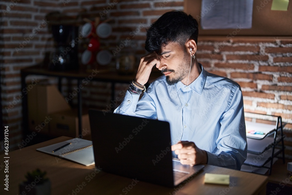 Young hispanic man with beard working at the office at night tired rubbing nose and eyes feeling fatigue and headache. stress and frustration concept. Young hispanic man with beard working at the office at night tired rubbing nose and eyes feeling fatigue and headache. stress and frustration concept.