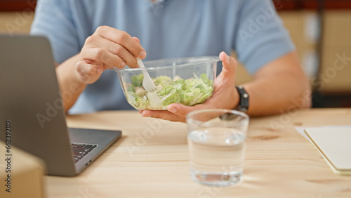 Grey-haired man ecommerce business eating salad at office