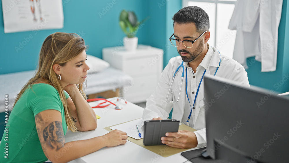 Obraz premium Man and woman doctor having medical consultation looking touchpad at the clinic