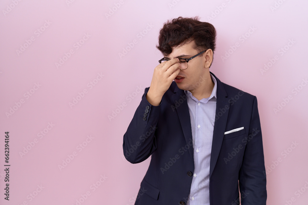 Young non binary man with beard wearing suit and tie tired rubbing nose and eyes feeling fatigue and headache. stress and frustration concept. Young non binary man with beard wearing suit and tie tired rubbing nose and eyes feeling fatigue and headache. stress and frustration concept.