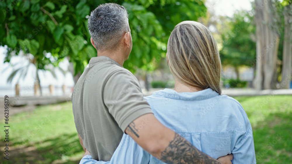 Fototapeta premium Man and woman couple hugging each other standing backwards at park
