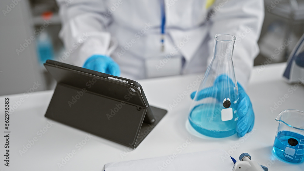 Woman scientist's hands expertly measuring liquid in test tube at lab, engaging in serious research with touchpad at her disposal Woman scientist's hands expertly measuring liquid in test tube at lab, engaging in serious research with touchpad at her disposal