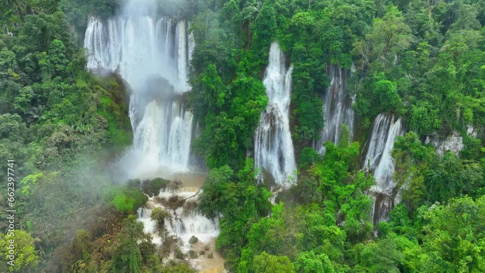 Jungle paradise: A mesmerizing view of a secluded waterfall concealed within the dense, vibrant green embrace of the tropical rainforest, as seen through the lens of a drone. Thailand. 4K HDR.
