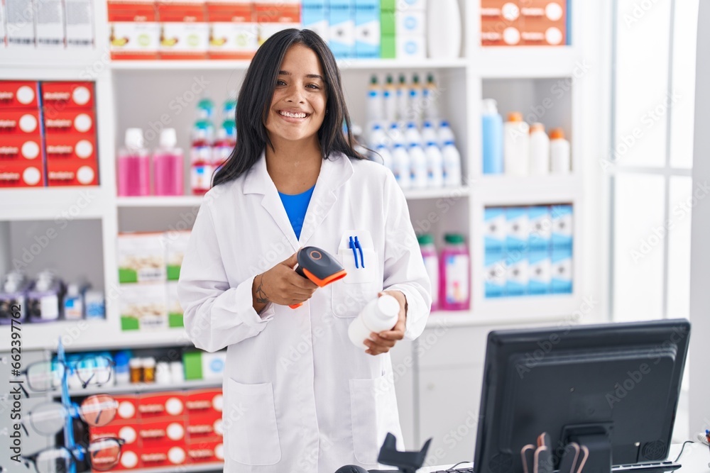 Young hispanic woman pharmacist scanning pills bottle at pharmacy