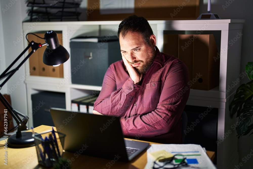 Plus size hispanic man with beard working at the office at night thinking looking tired and bored with depression problems with crossed arms. Plus size hispanic man with beard working at the office at night thinking looking tired and bored with depression problems with crossed arms.