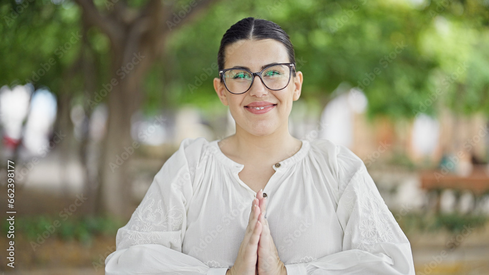 Young beautiful hispanic woman smiling praying at the park Young beautiful hispanic woman smiling praying at the park