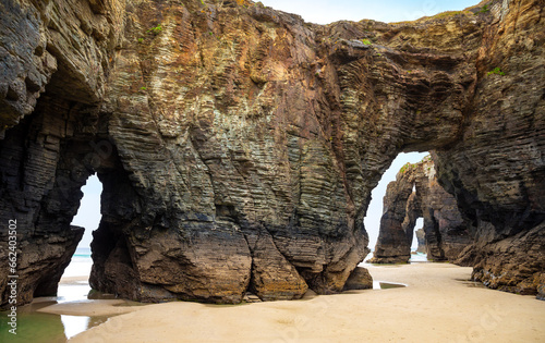 Natural rock arches Cathedrals beach, Playa de las Catedrales at Ribadeo, Galicia, Spain. Famous beach in Northern Spain Atlantic. Natural rock arch on Cathedrals beach in low tide photo