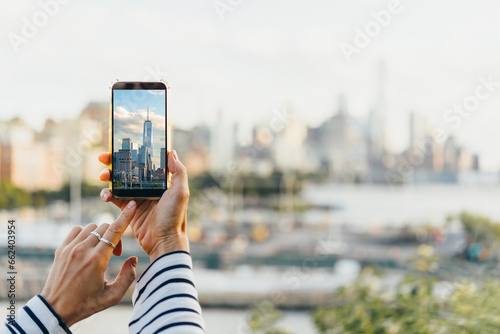 A person takes a mobile photo of the New York City's skyline seen from the bank of Hudson river at the West side of New York City, United States.