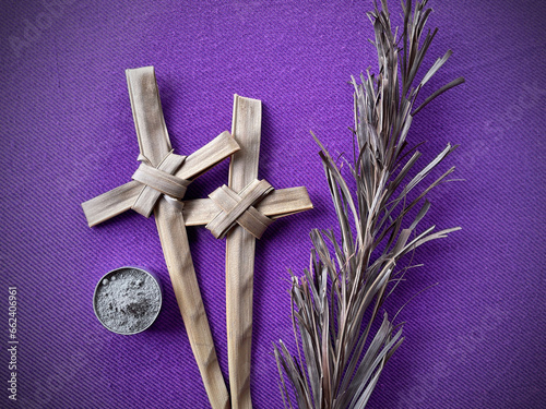 Christianity concept about Good Friday, Lent Season and Holy Week. Background of dry palm leaves, Holy Ashes and Holy Crosses made of palm leaf on purple background. photo