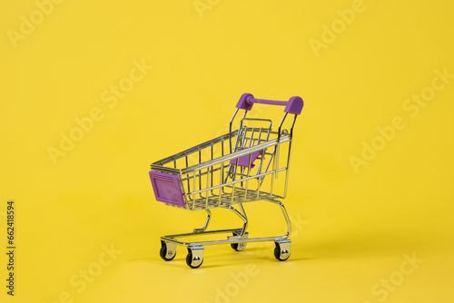 Small shopping cart in a supermarket. On a uniform yellow background.
