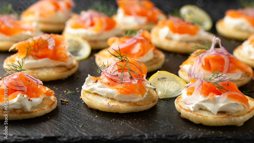 Mini blini pancakes with soft cheese, cold smoked salmon and dill photo