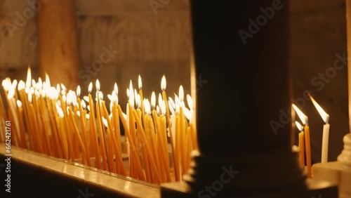 Burning candles in the Church of the Holy Sepulchre lighting the dark room. Visitors light candles in religious and most holy church in Old City of Jerusalem. Close up on yellow candles