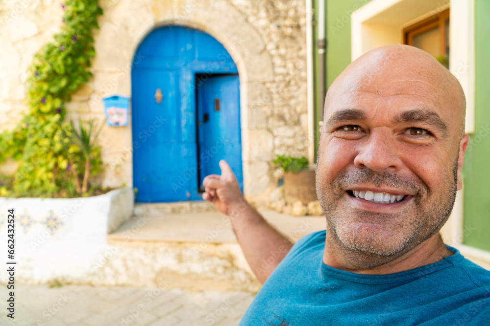  Smiling man takes a selfiewith a beautiful blue door on background - obrazy, fototapety, plakaty 