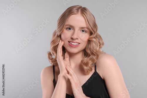 Portrait of beautiful woman with blonde hair on light grey background