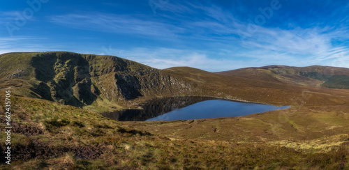 Beautiful vista, panorama with heart shaped lake, Lough Ouler, reflecting blue sky and Tonelagee Mountain. Hiking in Wicklow Mountains, Ireland