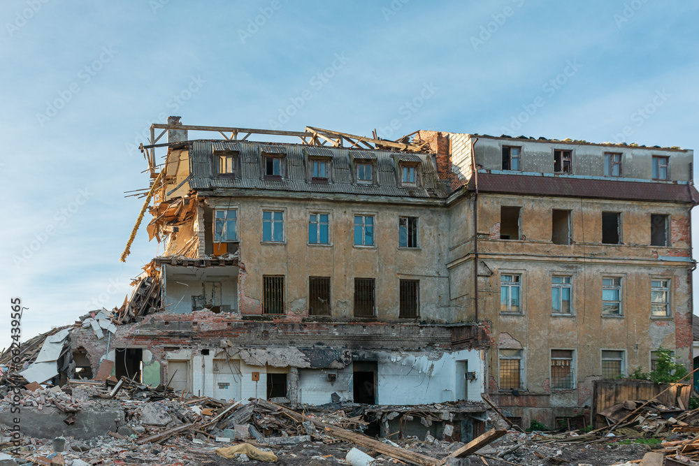 A large destroyed building with broken apartments and a pile of construction debris. House damaged by terrorist attack, war or earthquake background