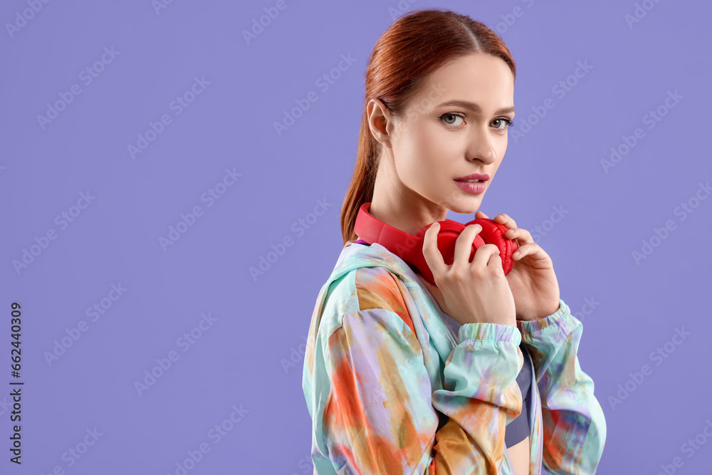 Young woman in sportswear and headphones on violet background, space for text Young woman in sportswear and headphones on violet background, space for text