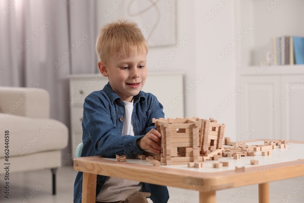 Cute little boy playing with wooden blocks at table indoors. Child's toy Cute little boy playing with wooden blocks at table indoors. Child's toy