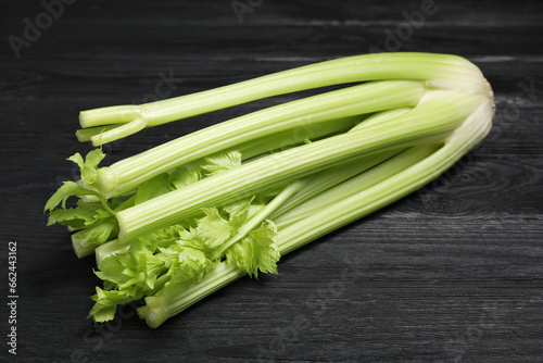 One fresh green celery bunch on black wooden table, closeup