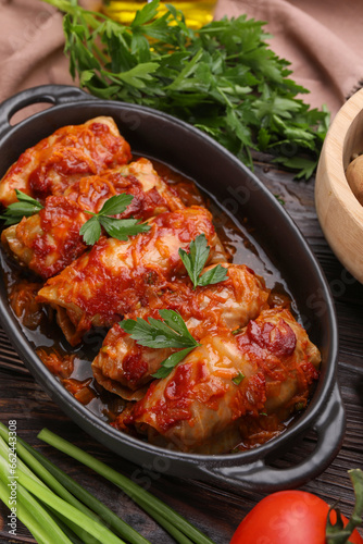 Delicious stuffed cabbage rolls cooked with tomato sauce on wooden table
