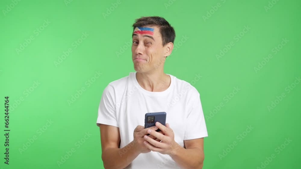 Philippines supporter looking at his mobile smiling and showing it. Philippines supporter looking at his mobile smiling and showing it.