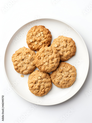 Top view of fresh baked oatmeal cookies on baking rack, white plate and white background	