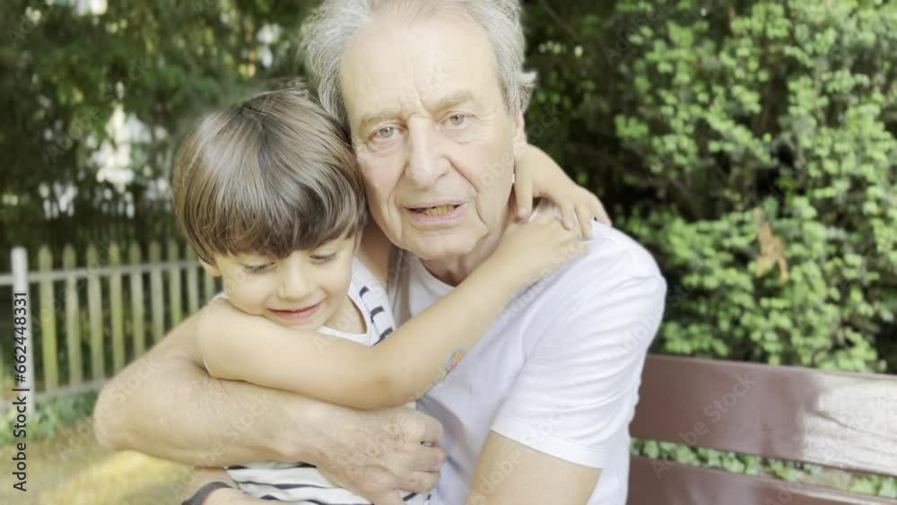Affectionate Boy Hugs His Grandpa on the Park Bench Affectionate Boy Hugs His Grandpa on the Park Bench