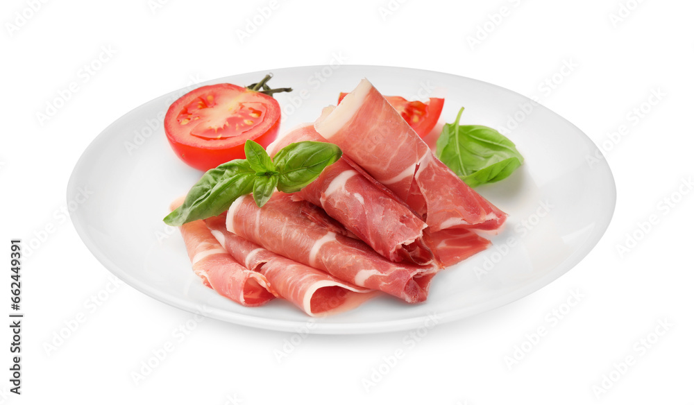 Plate with rolled slices of delicious jamon, cut tomato and basil isolated on white