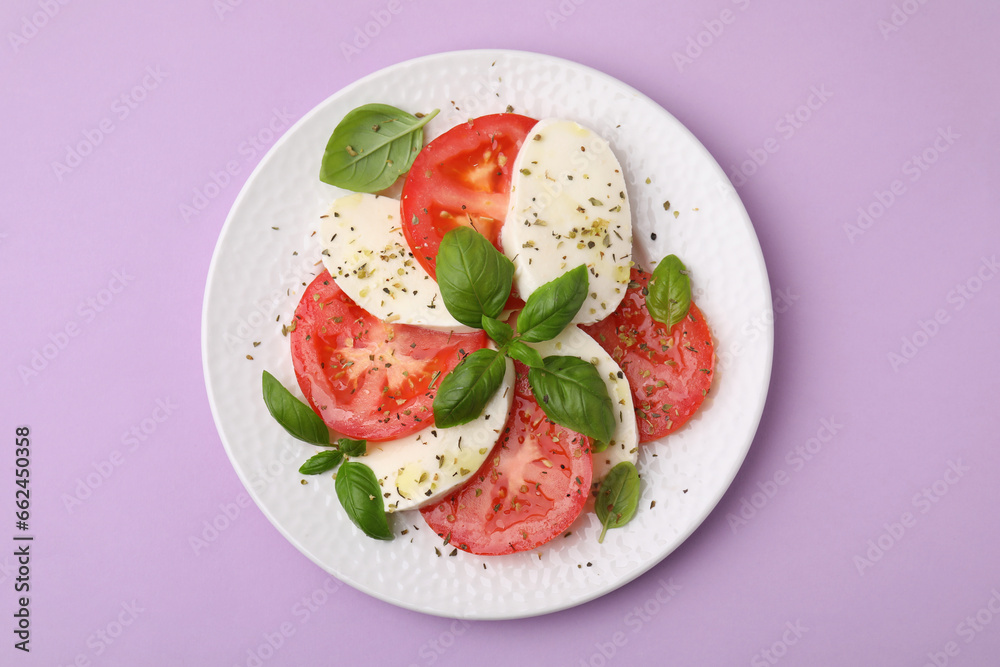 Plate of delicious Caprese salad with herbs on violet table, top view Plate of delicious Caprese salad with herbs on violet table, top view
