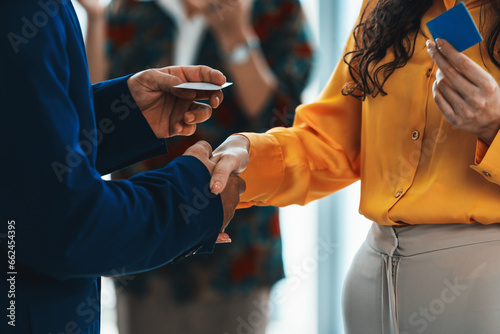 Businessmen shaking hand and making a contract in the sign of agreement, cooperation with businesswoman. Cropped image of managers holding business cards. Their partners standing behind. Intellectual.