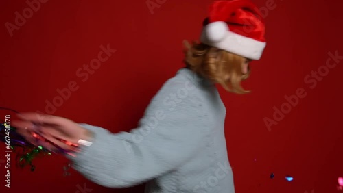 Young girl in Santa Claus cap playing with colorfull confetti and celebrate christmas. Concept christmas