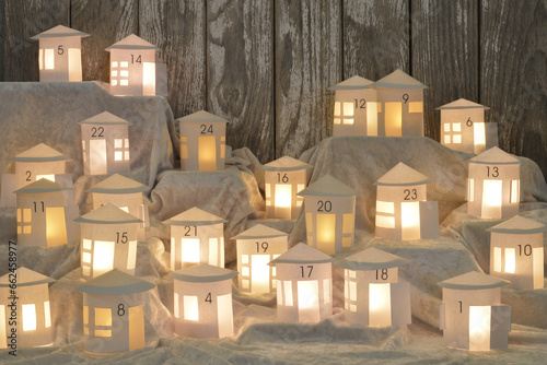 Advent calendar out of 24 self small made white round paper houses illuminated from the inside on white satin for Advent