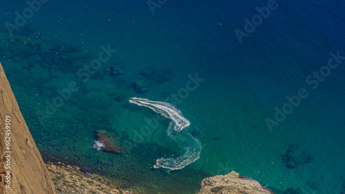 Estelas de Motos de agua junto a u acantilado con aguas transparentes color turquesa 