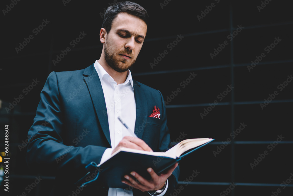 Male manager in formal analyzing schedule with day planner at city street Male manager in formal analyzing schedule with day planner at city street