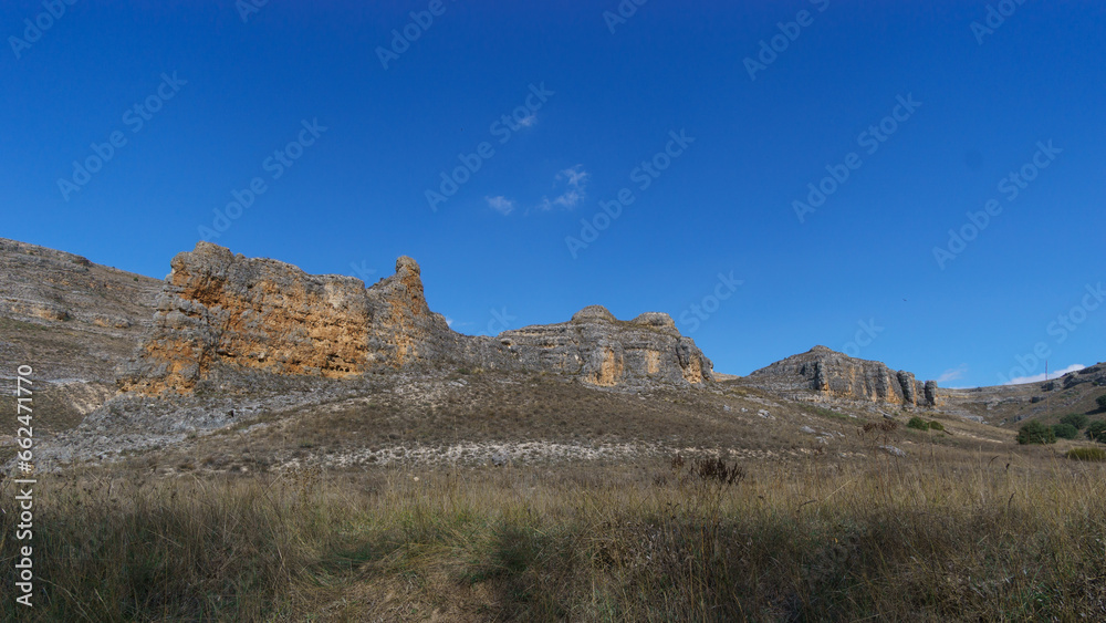 Rock formations with dry grass land in foreground Hoces del Duraton natural park near Sepulveda, Segovia, Spain