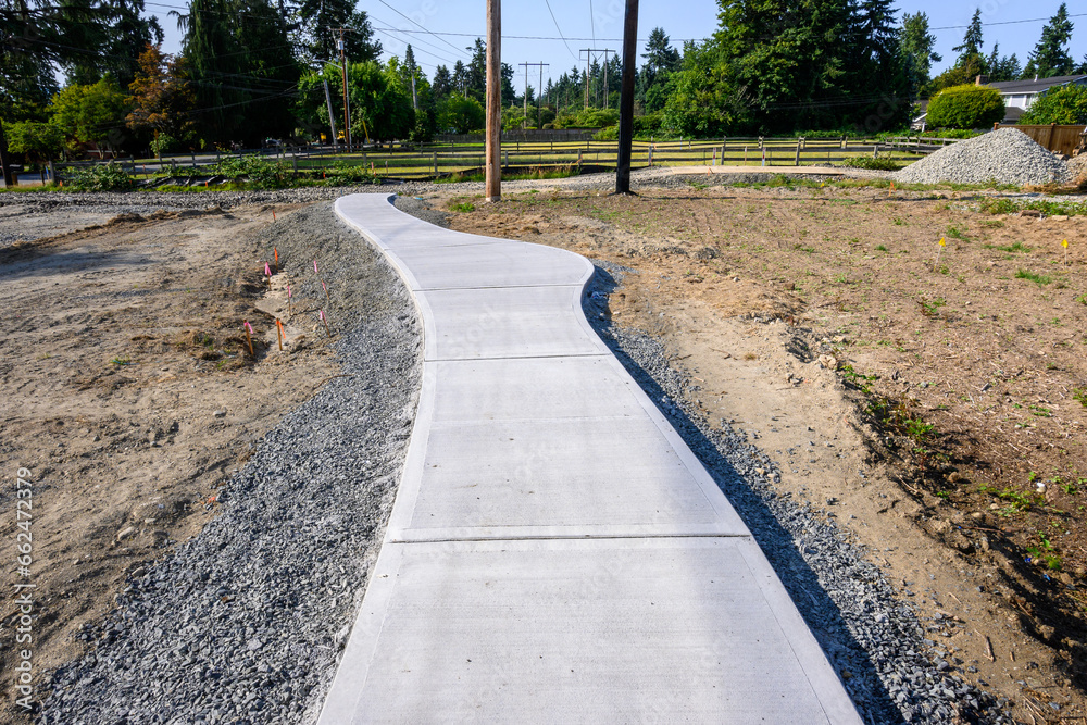 New residential community construction site, freshly poured concrete sidewalk and fresh dirt
