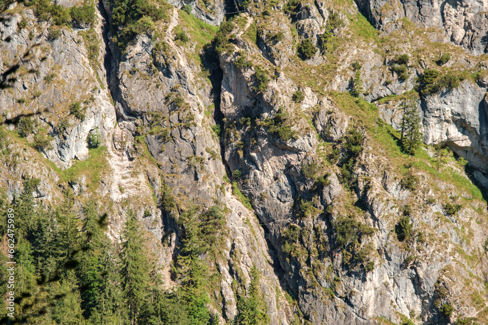 Nahaufnahme einer Felswand mit Wanderern im Klettersteig Nahaufnahme einer Felswand mit Wanderern im Klettersteig