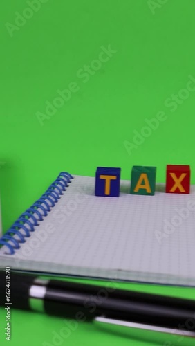 Tax written on colored wooden cubes. Notepad and calculator on the desk. Front view, chroma key. photo