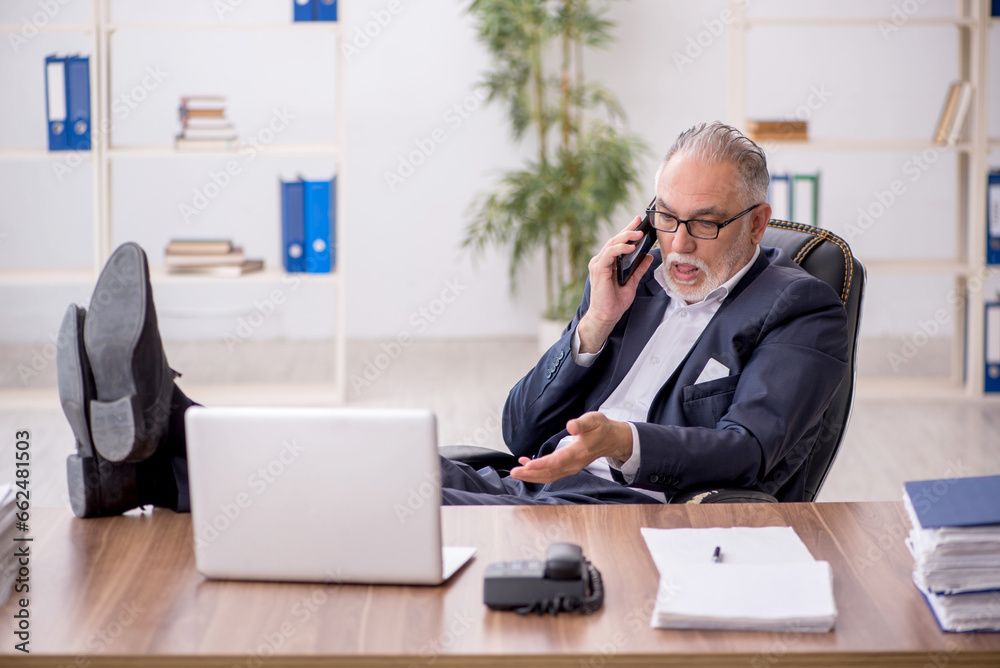Old male employee working in the office Old male employee working in the office