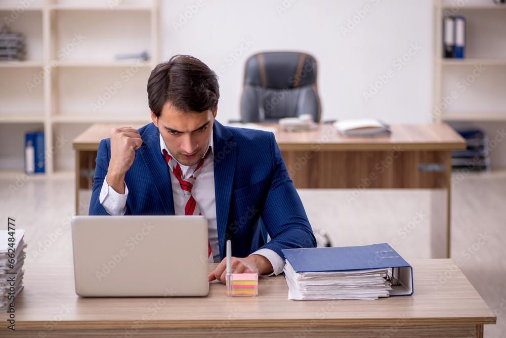 Young male employee and too much work in the office Young male employee and too much work in the office