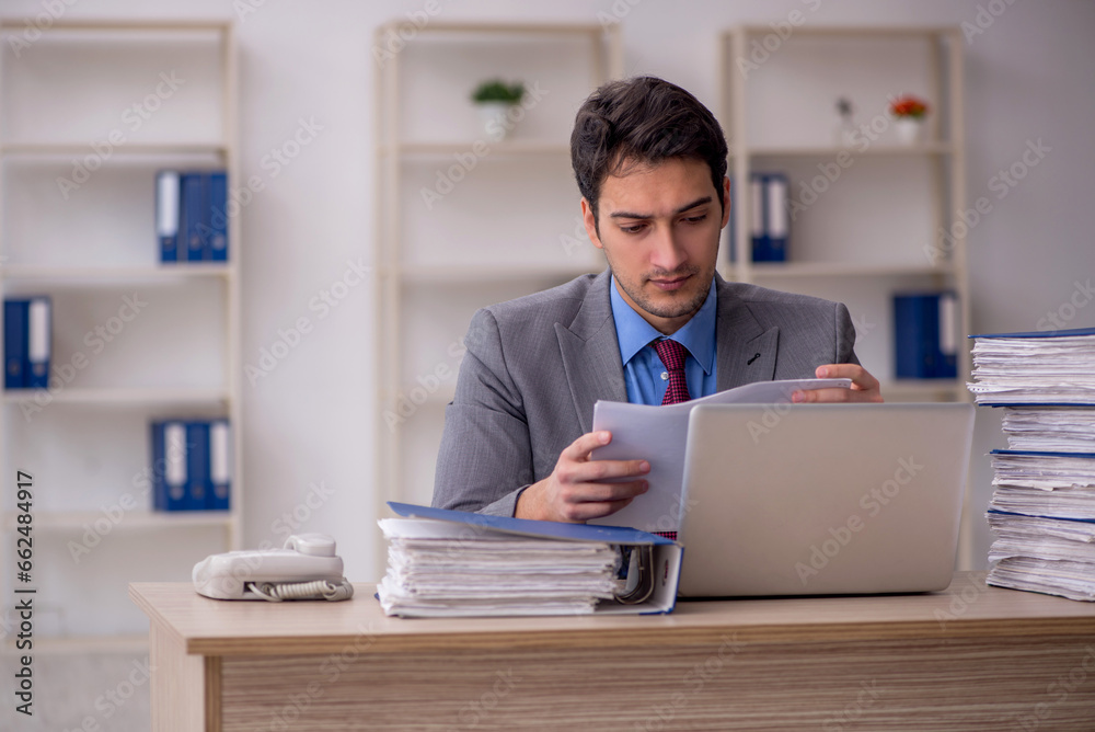 Young male employee and too much work in the office Young male employee and too much work in the office