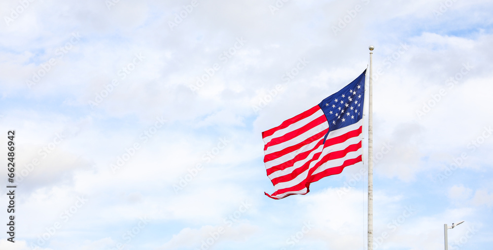 US flag waving in the wind against a blue sky. Symbol of freedom, unity, and national pride. Perfect for patriotic themes