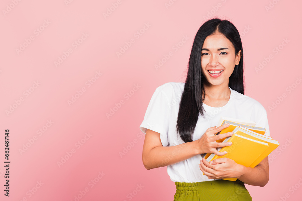 Portrait of beautiful Asian young woman teenage smiling hugging books, female person holding book multicolor, studio shot isolated on pink background with copy space, education concept Portrait of beautiful Asian young woman teenage smiling hugging books, female person holding book multicolor, studio shot isolated on pink background with copy space, education concept