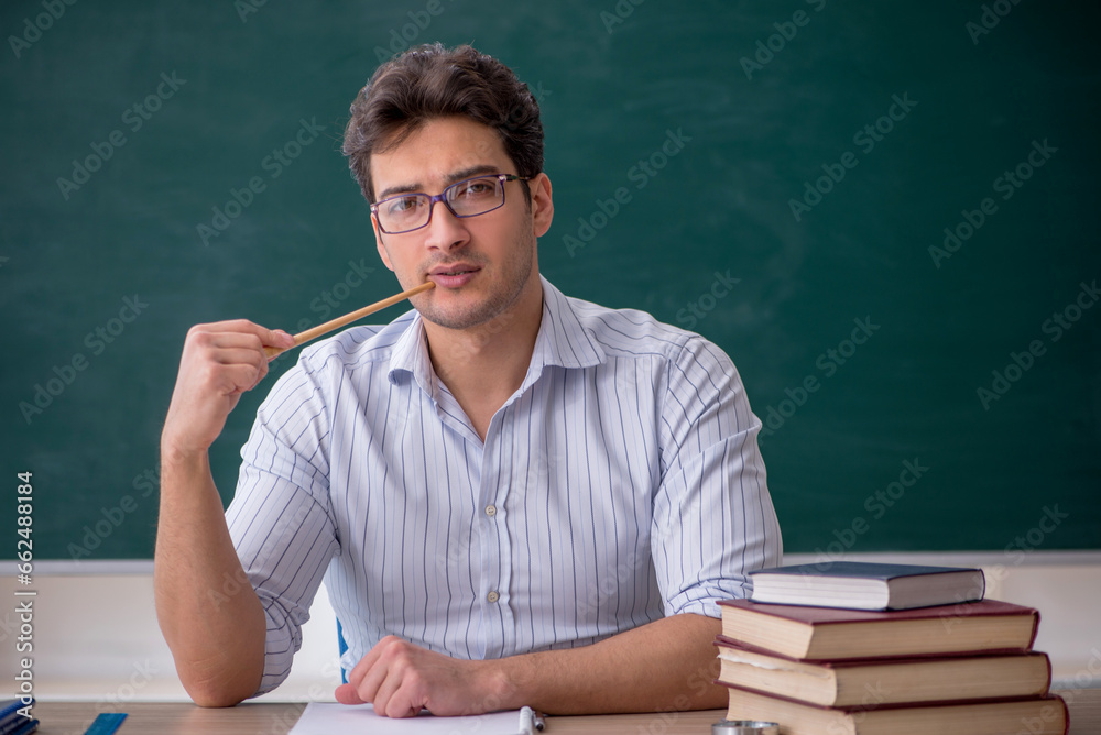 Young male teacher in front of green board Young male teacher in front of green board