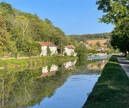 Burgundy canal, water reflecting surrounding forest and village