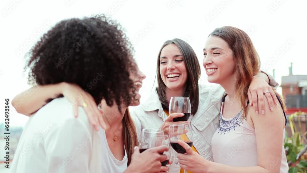Group of happy young women friends having fun gossiping while drinking and toasting wine glasses on a rooftop party. Joyful females smiling and clinking enjoying on a social event. Ladies talking Group of happy young women friends having fun gossiping while drinking and toasting wine glasses on a rooftop party. Joyful females smiling and clinking enjoying on a social event. Ladies talking
