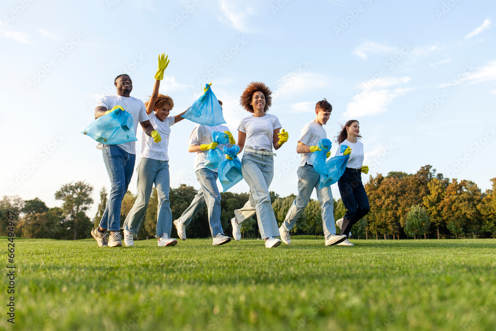 multiracial group of people running to clean the park from garbage and plastic with gloves and garbage bags multiracial group of people running to clean the park from garbage and plastic with gloves and garbage bags