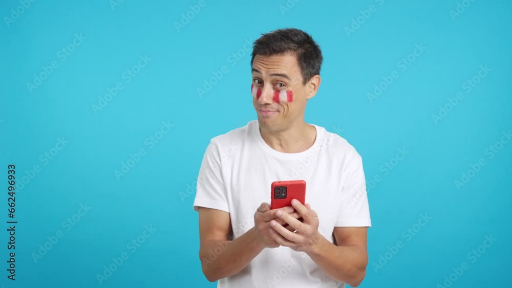 Peruvian supporter looking at his mobile smiling and showing it. Peruvian supporter looking at his mobile smiling and showing it.