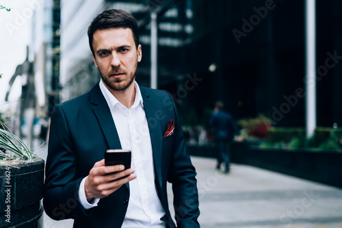 Serious businessman using smartphone on street