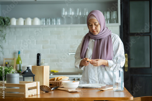 A Muslim woman is preparing to cook breakfast for her family. At the beautiful kitchen in her house  having fun woman with hijab preparing dinner  Islamic woman Enjoying Doing Homemade.